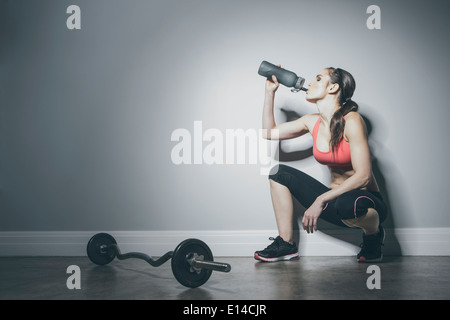 La donna caucasica in sportswear bere da una bottiglia d'acqua Foto Stock