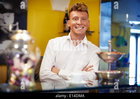 Persone in caffetteria, ritratto di felice giovane uomo che lavora come barman, sorridente in telecamera dietro il contatore Foto Stock