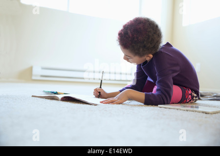 Razza mista ragazza disegno sul pavimento della camera Foto Stock