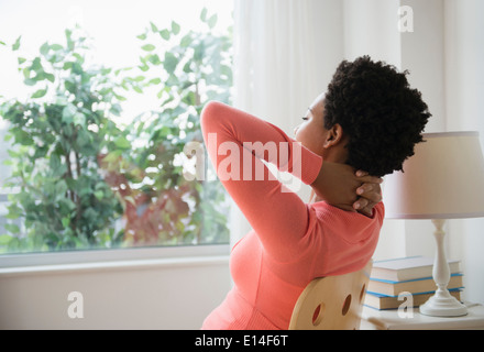 Nero donna in un momento di relax a finestra con le mani dietro la testa Foto Stock