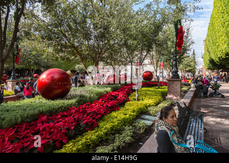 Donna messicana rilassante in un plaza, Jardin Zenea, adornata con decorazioni di Natale, a Queretaro, Messico Foto Stock