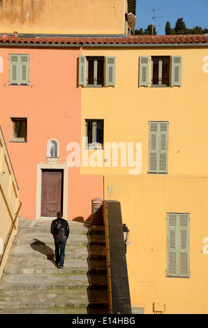 Uomo passaggi di arrampicata nella Città Vecchia o il centro storico di Menton con Orange & Case giallo Menton Alpes-Maritimes Francia Foto Stock