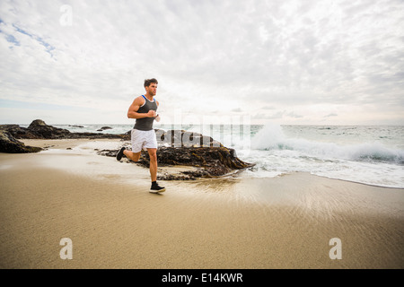 Uomo caucasico in esecuzione sulla spiaggia Foto Stock