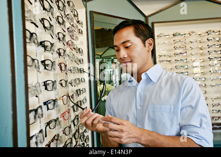 Uomo filippino cercando sui bicchieri a all'ottico optometrista Foto Stock