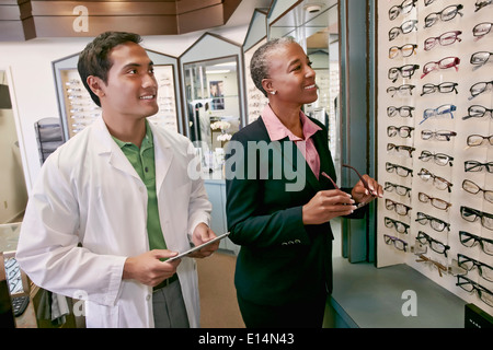 Donna cerca su vetri a all'ottico optometrista Foto Stock