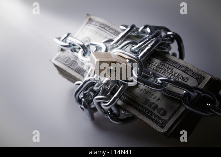 Catene e lucchetti intorno a pila di fatture del dollaro Foto Stock