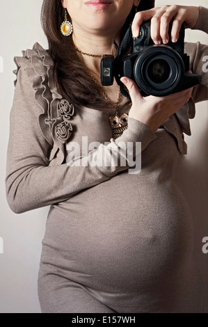 Immagine della donna incinta prendendo autoritratto con fotocamera reflex digitale Foto Stock