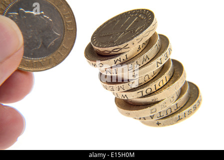 Pila di libbra di monete in euro con una mano che tiene un due pound coin Foto Stock