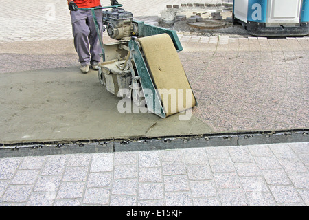 Lavoratore con macchina, intonacando composto street pavimentato con mattoni Foto Stock