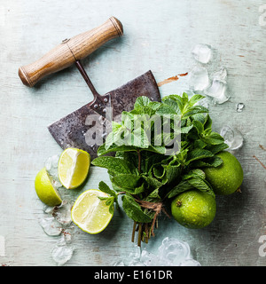 Ingredienti per rendere mojitos di cubetti di ghiaccio, foglie di menta e calce su sfondo blu Foto Stock