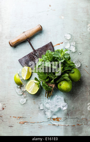 Ingredienti per rendere mojito. Cubetti di ghiaccio, foglie di menta e calce su sfondo blu Foto Stock