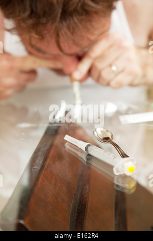 L'uomo abusa di cocaina o altro farmaco in polvere. Profondità di campo con il focus sulla siringa in primo piano. Foto Stock