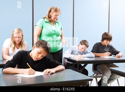 La supervisione degli insegnanti di alta scuola gli studenti che prendono e raggiungimento prova. Foto Stock