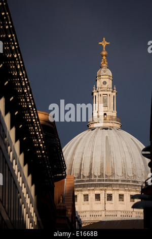 La Cattedrale di St Paul e cupola vista tra gli edifici lungo la strada nel drammatico luce storm con Dark Sky City di Londra Inghilterra REGNO UNITO Foto Stock