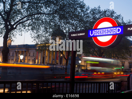 Trafalgar Square stazione metropolitana di firmare con la cupola della Galleria Nazionale e del traffico su strada dietro a Londra England Regno Unito Foto Stock