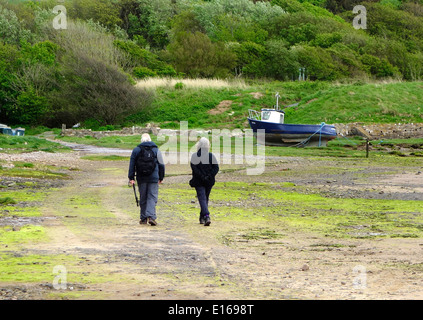 Senior Caucasain giovane camminando lungo la spiaggia di Ravenglass, Parco Nazionale del Distretto dei Laghi, Cumbria, England, Regno Unito Foto Stock
