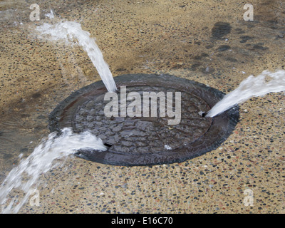 Perde acqua di rete in Oslo Norvegia cambiando il chiusino in una fontana Foto Stock