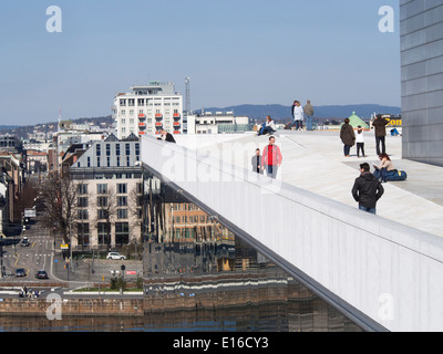 Turisti che si godono la vista dal tetto dell'Opera in Oslo Norvegia, frazioni riflessa dalla facciata in vetro Foto Stock