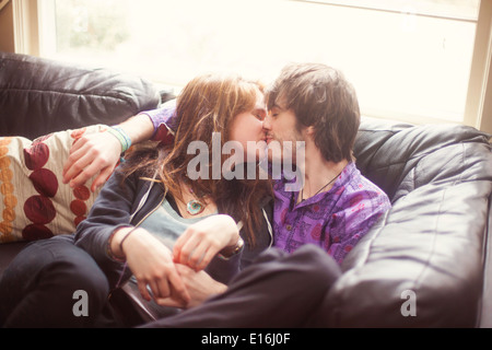 Coppia giovane seduto sul divano e baciare Foto Stock