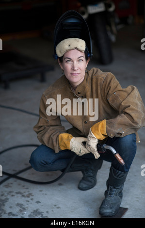 Saldatore femminile al lavoro nel suo garage Foto Stock