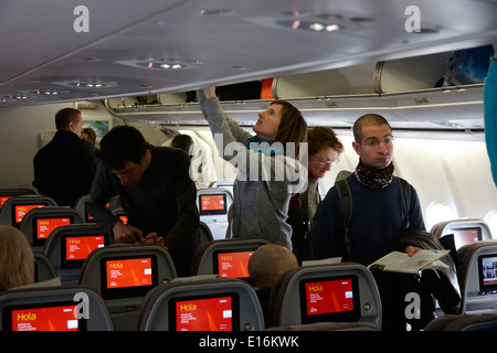 Carico di passeggeri negli armadietti soprastanti e il poggiatesta schermo per intrattenimenti a bordo iberia airbus spagna Foto Stock