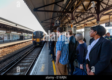 Pendolari in attesa di un treno, Clapham Junction stazione ferroviaria di Londra, Inghilterra Foto Stock