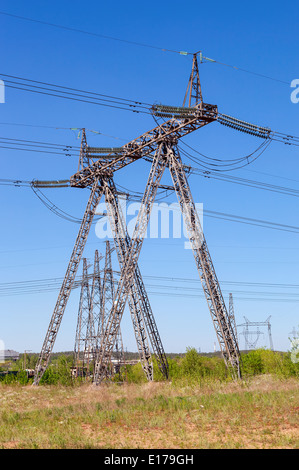 Standard overhead power line transmission tower against blue sky Foto Stock
