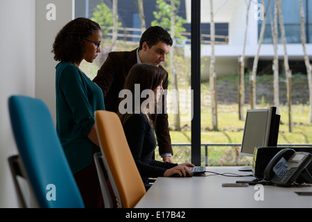 Gli impiegati a discutere di un progetto mentre guardando lo schermo di un computer Foto Stock