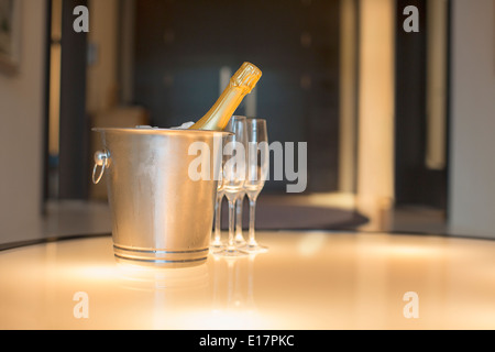 Champagne in argento secchio accanto a flute da champagne Foto Stock