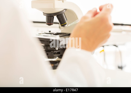 Scienziato usando microscopio in laboratorio Foto Stock