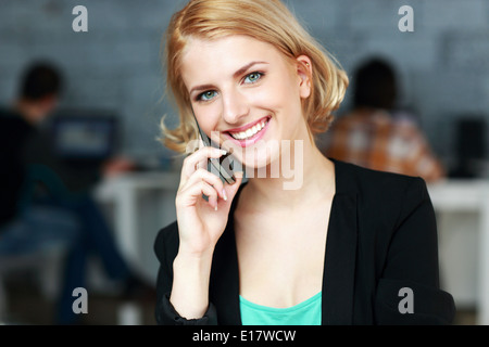 Felice imprenditrice parlando al telefono in ufficio Foto Stock