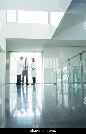 I medici e gli amministratori a parlare nel corridoio di ospedale Foto Stock