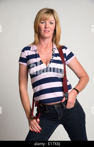 Ritratto di una donna in camicia a righe che indossa jeans e bretelle Foto Stock