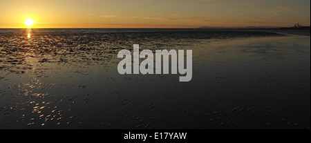 Irlandese arancione tramonto sul mare splendente su sabbia bagnata increspature spiaggia, verso Blackpool e monti Pennini, da St Annes Foto Stock