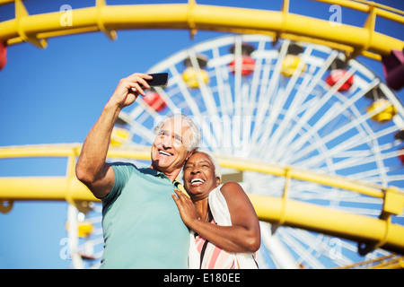 Coppia senior tenendo selfie presso il parco di divertimenti Foto Stock