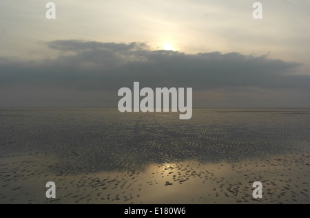 Veicolo piste che attraversano sabbia bagnata increspature spiaggia con riflessi verso il sole che tramonta sotto nuvole grigie, St Annes, costa di Fylde, Regno Unito Foto Stock