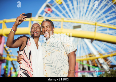Coppia senior tenendo selfie presso il parco di divertimenti Foto Stock
