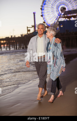 Coppia senior camminando sulla spiaggia al tramonto Foto Stock