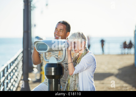 Coppia senior con gettoniera binocolo sul molo Foto Stock