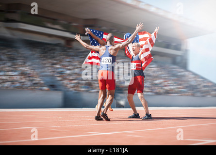 Guide di scorrimento per celebrare e tenendo bandierine americane sulla via Foto Stock