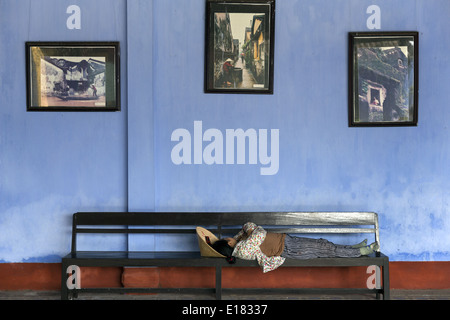 Una donna che dorme sdraiato su una panchina di Hoa Trung Assembly Hall Foto Stock