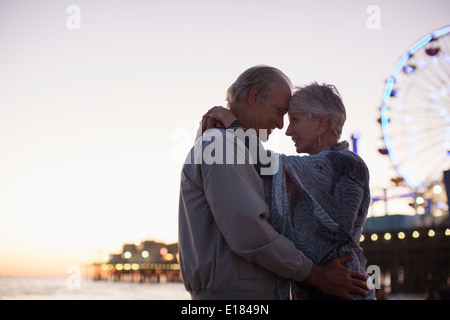 Coppia senior costeggiata sulla spiaggia al tramonto Foto Stock