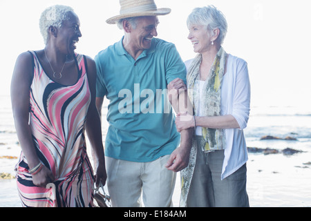 Senior amici camminando sulla spiaggia Foto Stock