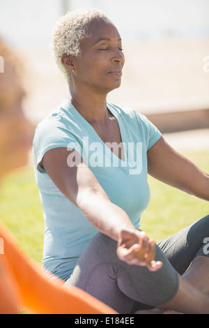 Serena donna meditando nella posizione del loto all'aperto Foto Stock