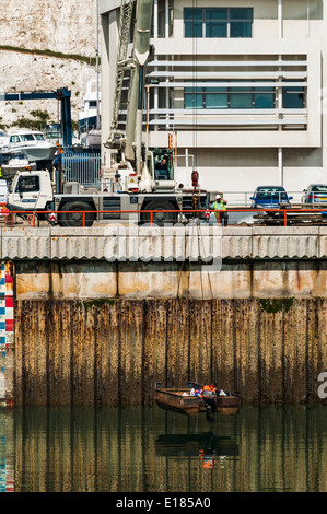 Piccola barca in metallo che viene sollevato fuori dall'acqua per mezzo di una gru a Brighton Marina Foto Stock