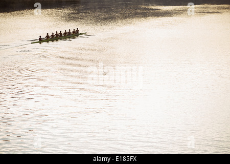 Il team di canottaggio in scull sul lago di sole Foto Stock