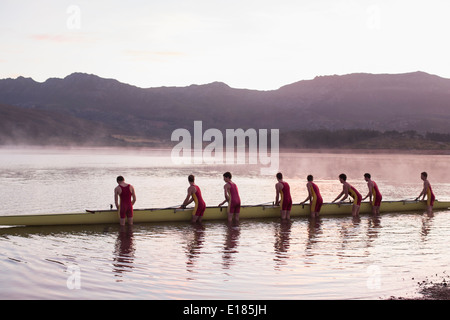 Equipaggio di canottaggio scull immissione nel lago all'alba Foto Stock