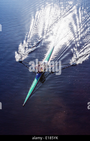 Uomo scull canottaggio sul lago Foto Stock