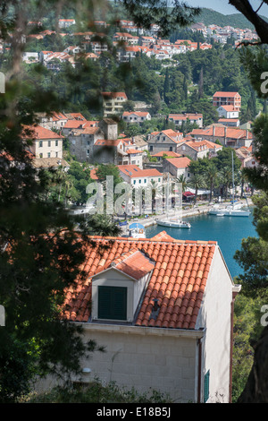 Una vista del mare attraverso alcuni alberi, Cavtat, con barche ormeggiate sulla baia, Croazia, Europa Foto Stock