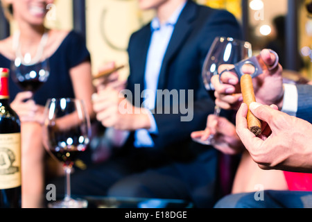 Close up uomo asiatico del taglio a mano il sigaro in ristorante Foto Stock